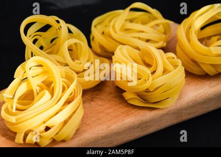 Pasta all'uovo, Tagliatelle Pasta, sfere rotonde di pasta cruda su fondo nero Foto Stock