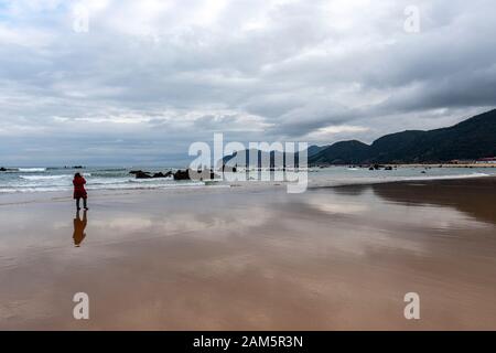 Fotografo donna che scatta foto di Rocks a Playa de Trengandín, Noja, Cantabria, Spagna Foto Stock