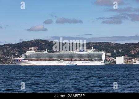 Nave da crociera Azura con partenza dal porto di Bergen, Norvegia. Nave da pesca piccola Svebas essendo sordata contro la grande nave da crociera. Foto Stock