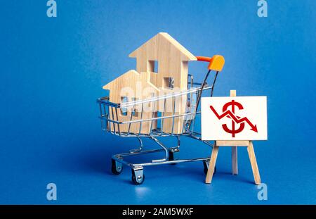 Case in legno in un carrello e un cavalletto con una freccia rossa del dollaro verso il basso. Caduta del mercato immobiliare. Affitto economico. Riduzione della domanda, recessione. L Foto Stock