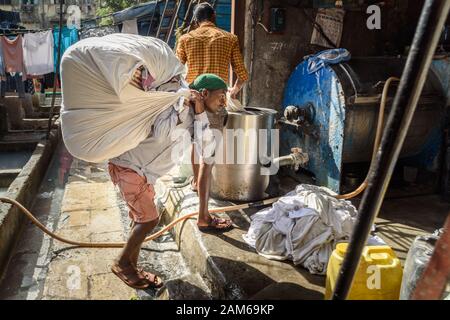 Indian woker portare borse di vestiti a Dhobi Ghat è lavanderia all'aperto a Mumbai. India Foto Stock