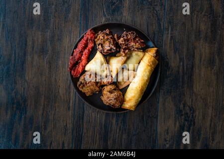 Il cibo indiano piastra con pollo, Pakora, Aloo Tikki, Samosas Samsa e involtini primavera. I cibi tradizionali. Foto Stock