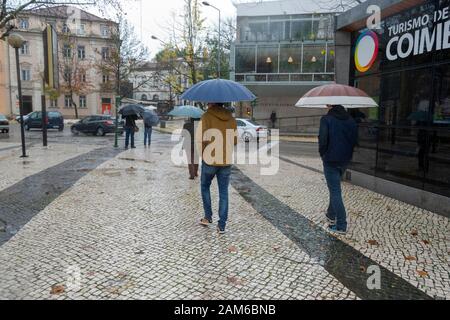COIMBRA, PORTOGALLO - 04 gennaio 2016 - le persone cercano di rimanere asciutte durante le piogge intense nella Repubblica di Praca nel centro di Coimbra, Portogallo Foto Stock
