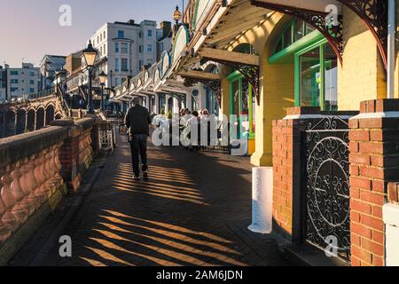 Ramsgate, Regno Unito - 30 dicembre 2019. Il basso sole del pomeriggio splende attraverso la balaustra formando ombre sul sentiero e illuminando le caffetterie e il restaura Foto Stock