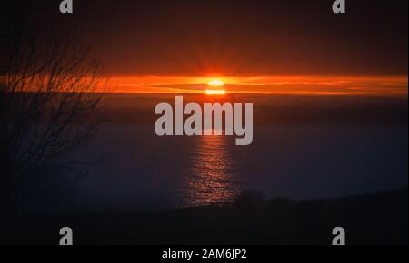 Il sole che si riflette nel mare di Pegwell Bay e che forma raggi solari Foto Stock