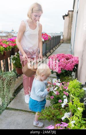 Giovane madre con la sua bambina baia ragazza annaffiatura fiori Foto Stock