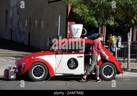 Un giovane imprenditore vende caffè appena estratto dal suo bug Volkswagen nel centro di Denver, Colorado USA Foto Stock