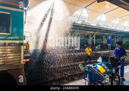 Bangkok/Thailandia-Dicembre 2019: Personale addetto alla pulizia della stazione in tute blu al lavoro, lavaggio del treno diretto per la partenza con spruzzi d'acqua a hua lamphong Foto Stock