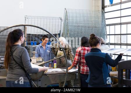 Volontari tiene fresco stampe dello schermo per il rack di asciugatura al Pratt Fine Arts Center di Sabato, 11 gennaio 2020. Guidato da artista Claire Jauregui (centro maglietta blu) per il quarto anno consecutivo, i membri del pubblico sono stati invitati a schermata Help Stampare manifesti da artisti locali a sostegno della prossima Womxn del marzo a Seattle. Schermo di seta disegni sono stati forniti da artisti Eileen Jimenez, Lynda Sherman e Leigh Riibe. Il rally e marzo, organizzato da Seattle Womxn marciare in avanti, si terrà il 18 gennaio 2020. Foto Stock