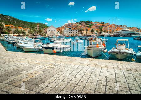 Popolare resort medievale mediterraneo con splendido porto e maestoso paesaggio urbano. Barche di lusso, barche a vela e barche da pesca ancorate a Hvar a. Foto Stock