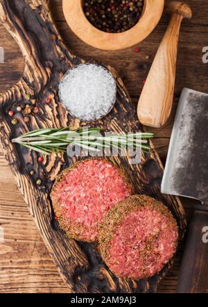 Crudo fresco pepe tritato hamburger di manzo su vintage tagliere con mortaio e pestello e carne ascia di guerra su uno sfondo di legno. Foto Stock