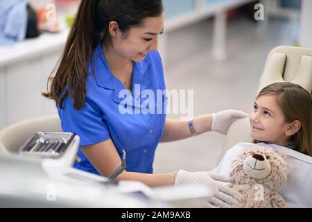 Cute piccolo capretto e il suo orsacchiotto in visita il dentista Foto Stock