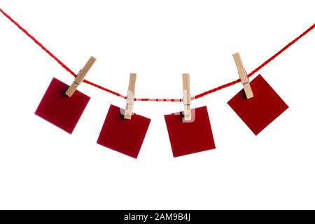 Set di quattro rosso vuoto note di carta tenuto su una stringa con clothespins isolati su sfondo bianco Foto Stock