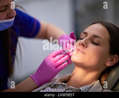 Donna che ha il trattamento del labbro per l'elevazione degli angoli della bocca e la rimozione delle linee della marionette Foto Stock