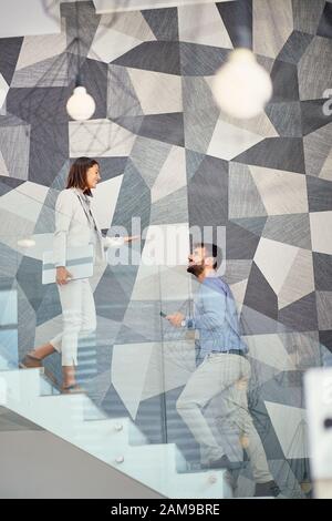 Uomini d'affari che sorridono sulle scale dell'edificio degli affari. Foto Stock