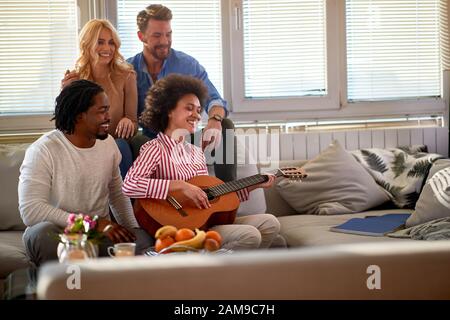 La giovane donna suona la chitarra termina con gli amici Foto Stock