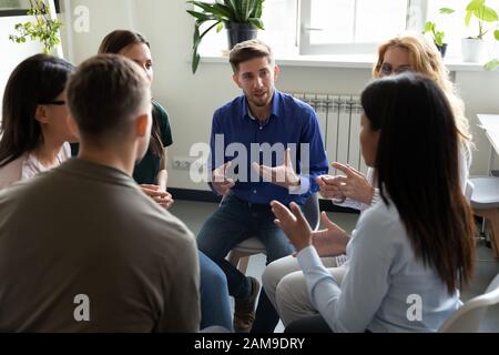 Persone diverse seduti in cerchio che partecipano alla sessione di terapia di gruppo Foto Stock