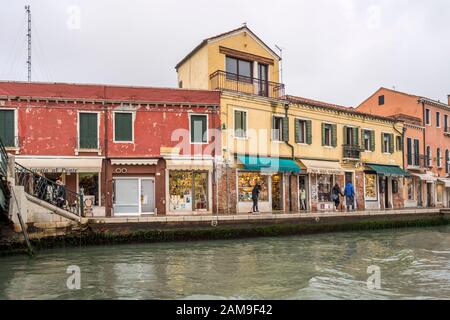 Venezia, ITALIA - 29 ottobre 2019: Paesaggio urbano con vecchie case e negozi sul lungofiume dei canali, girato il 29 ottobre 2019 in luminosa luce autunnale torbida a Muran Foto Stock