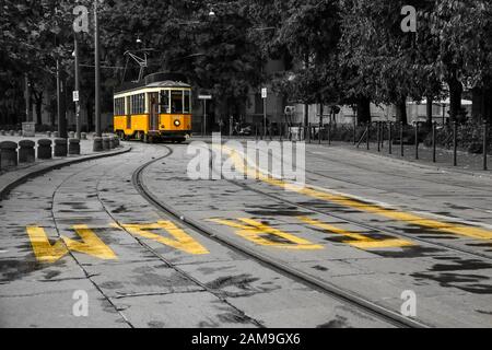 Una foto del tipico tram giallo a Milano, Italia, passando per il centro della città. Il tram è isolato su sfondo bianco e nero. Foto Stock