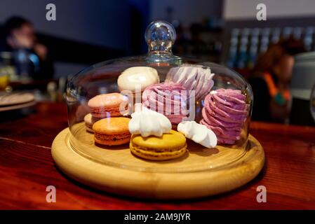 Pasticceria su un vassoio di legno sotto una cupola di vetro in una caffetteria. Foto Stock