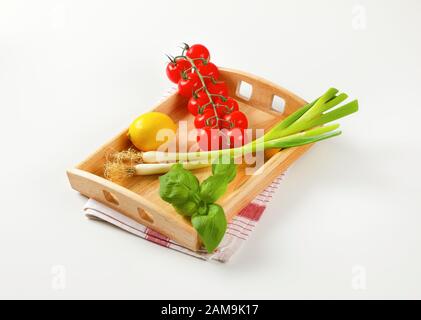 Verdure fresche e limone su vassoio di servizio in legno Foto Stock