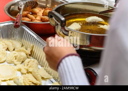 Lady Deep friggere tradizionale cinese Yau Kok Zai o dolce gnocco con alcuni crudo nelle vicinanze per il Capodanno cinese Foto Stock