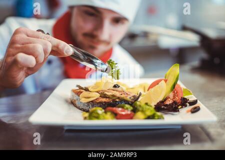 Orgoglioso chef che ha guarnito un piatto quasi finito nel ristorante con partenza Foto Stock