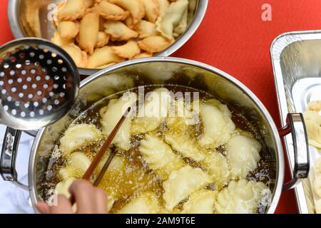 Lady Deep friggere tradizionale cinese Yau Kok Zai o dolce gnocco con alcuni crudo nelle vicinanze per il Capodanno cinese Foto Stock