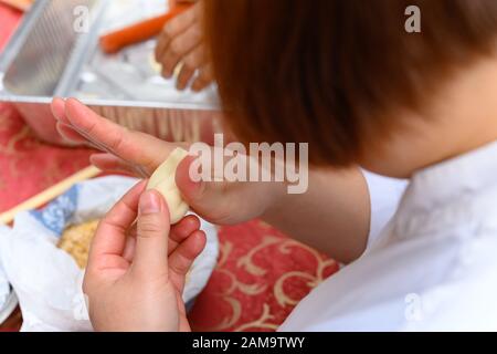 Lady Making tradizionale cinese Yau Kok Zai o dolce gnocco per il Capodanno cinese Foto Stock