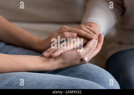 La figlia adulta di supporto tiene le mani di mamma senior Foto Stock