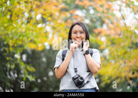 Giovane e bella fotografa con la macchina fotografica professionale che scatta la foto bella foglia d'acero colorata d'autunno a Kyoto Giappone. Foto Stock