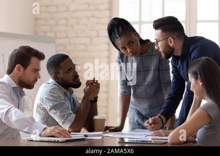 Diversi dipendenti millennial discutono del progetto aziendale durante la riunione Foto Stock