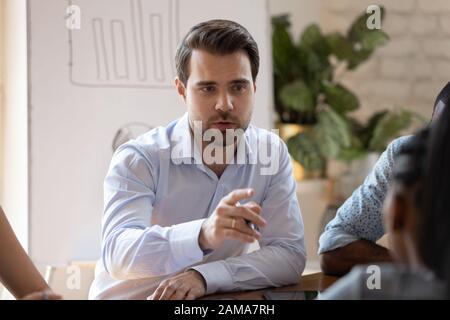 L'uomo d'affari caucasico parla con il collega durante il brainstorming alla riunione Foto Stock