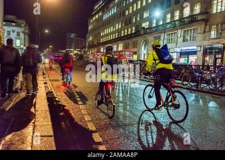 Lavoratori in ufficio che si trovano in bicicletta in un inverno buio ora di punta sera, Londra Foto Stock