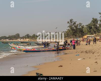 Nianing, Senegal - Gennaio 2, 2019: i pescatori la raccolta di pesce di legno colorato barca fisher permanente sulla spiaggia. Africa Foto Stock