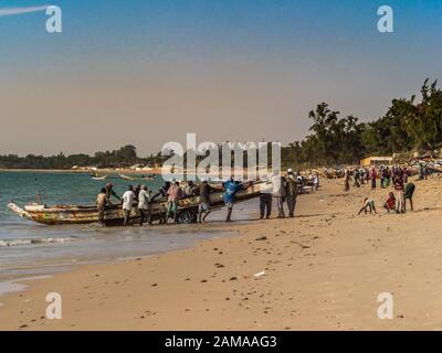 Nianing, Senegal - Gennaio 2, 2019: i pescatori la raccolta di pesce di legno colorato barca fisher permanente sulla spiaggia. Africa Foto Stock