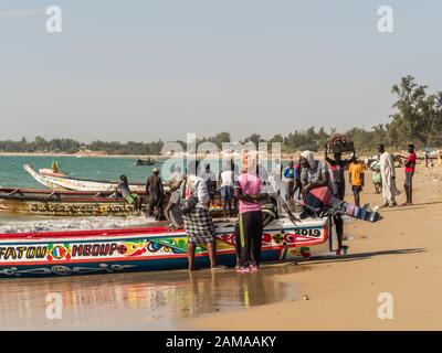 Nianing, Senegal - Gennaio 2, 2019: i pescatori la raccolta di pesce di legno colorato barca fisher permanente sulla spiaggia. Africa Foto Stock