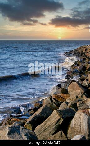 Banchi rocciosi lungo il fronte spiaggia con surf che si infrangono Foto Stock