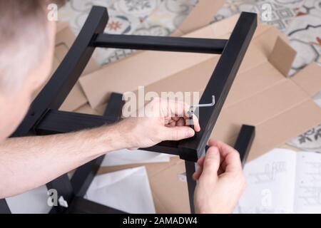 Uomo assemblaggio di mobili in legno con l'uso di utensili, primo piano. Lavori di carpenteria in officina. Foto Stock
