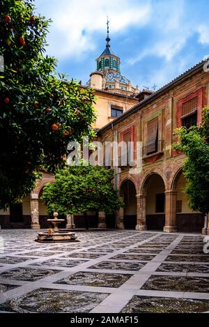 Vista del cortile interno in Granada con il rosso e orage facciata decorata palace. Foto Stock