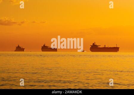 Le navi in attesa al di ancoraggio nel Golfo del Messico presso sunrise, prima di entrare in Galveston Bay sul loro modo al Porto di Houston, Texas, Stati Uniti d'America Foto Stock