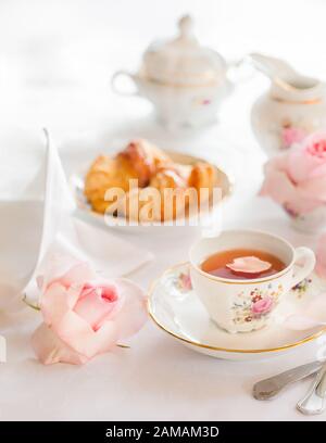 Colazione con tè, croissant e fragole fresche servite con raffinata porcellana set di rose Foto Stock