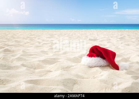 Primo piano Santa Hat su una spiaggia di sabbia bianca infinity caribbean. Natale Holiday Concetto Di Viaggio Foto Stock