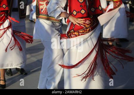 I ballerini professionisti del Timisul Folklore Ensemble tengono le mani in una danza tradizionale rumena indossando costumi tradizionali belli. Foto Stock