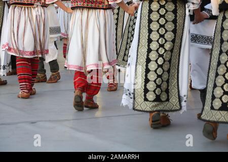 I ballerini professionisti del Timisul Folklore Ensemble tengono le mani in una danza tradizionale rumena indossando costumi tradizionali belli. Foto Stock