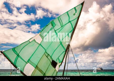 barca a vela polinesiana (Prau) sulla spiaggia dell'isola di Yanaba da Papua Nuova Guinea. Sullo sfondo si può vedere la nave spedizione True North Foto Stock