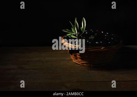 Un wiker cesto pieno con maturi freschi olive nere provenienti dalla Puglia, chiave di basso Foto Stock