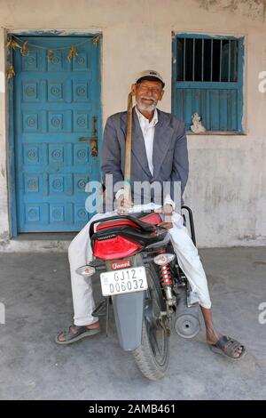 Anziano Man of the Rabari Tribe seduto su una moto Honda Maringana Village, Gujarat, India Foto Stock