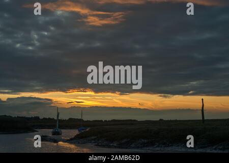 Tramonto scende oltre Brancaster Staithes sulla Costa North Norfolk Foto Stock