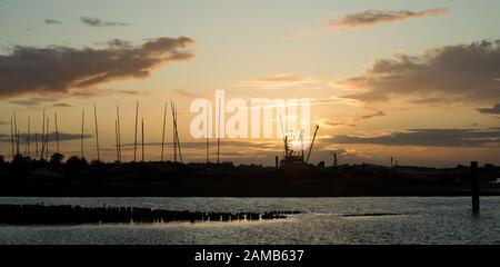 Immagine classica del tramonto che crea una splendida silhouette di Brancaster Staithes nel Nord Norfolk Foto Stock